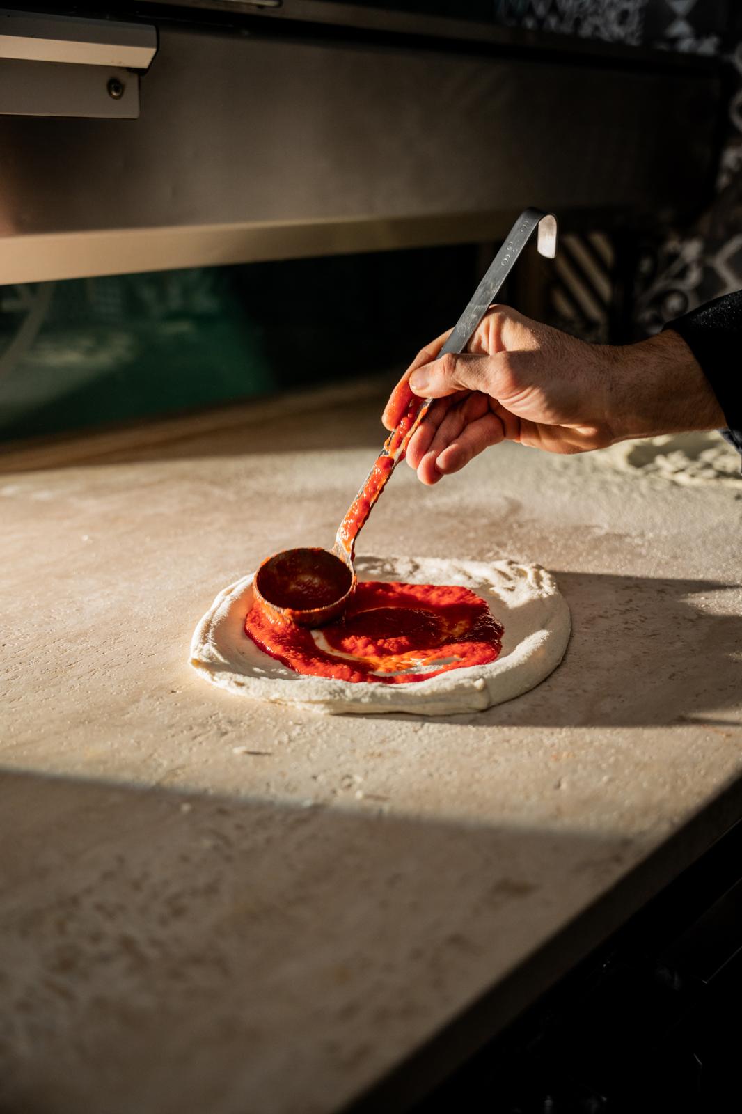 Preparazione pizza gourmet – L'Aforisma pizzeria artigianale Torino